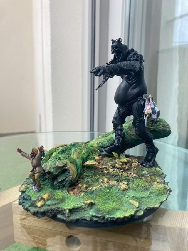 Diorama: a dark armoured figure and a huge black beast on a green base