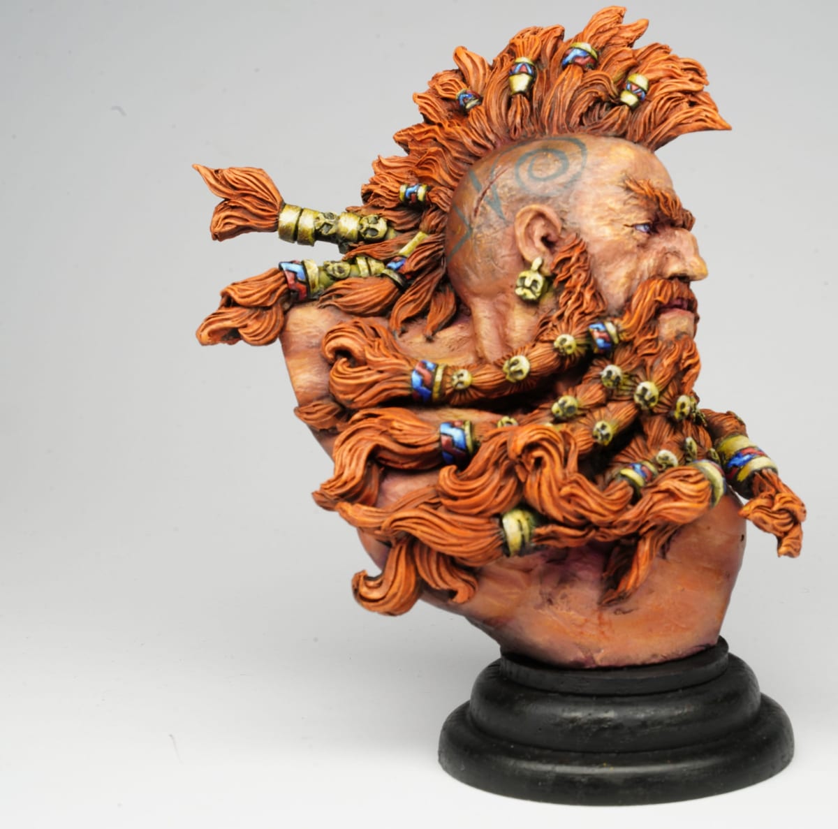 El busto de perfil: la barba naranja trenzada y los adornos