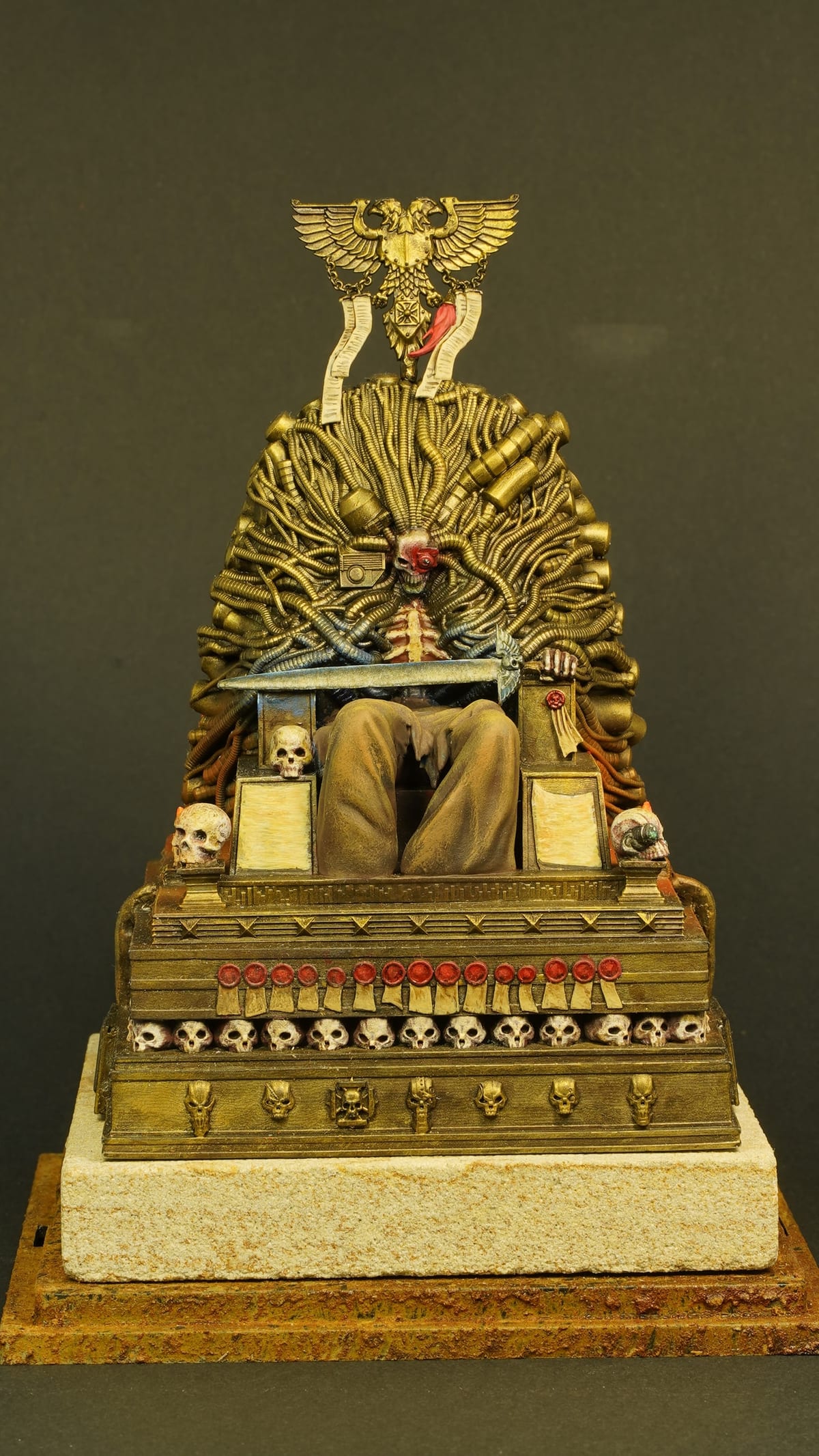 A seated figure on a tall golden throne decorated with skulls