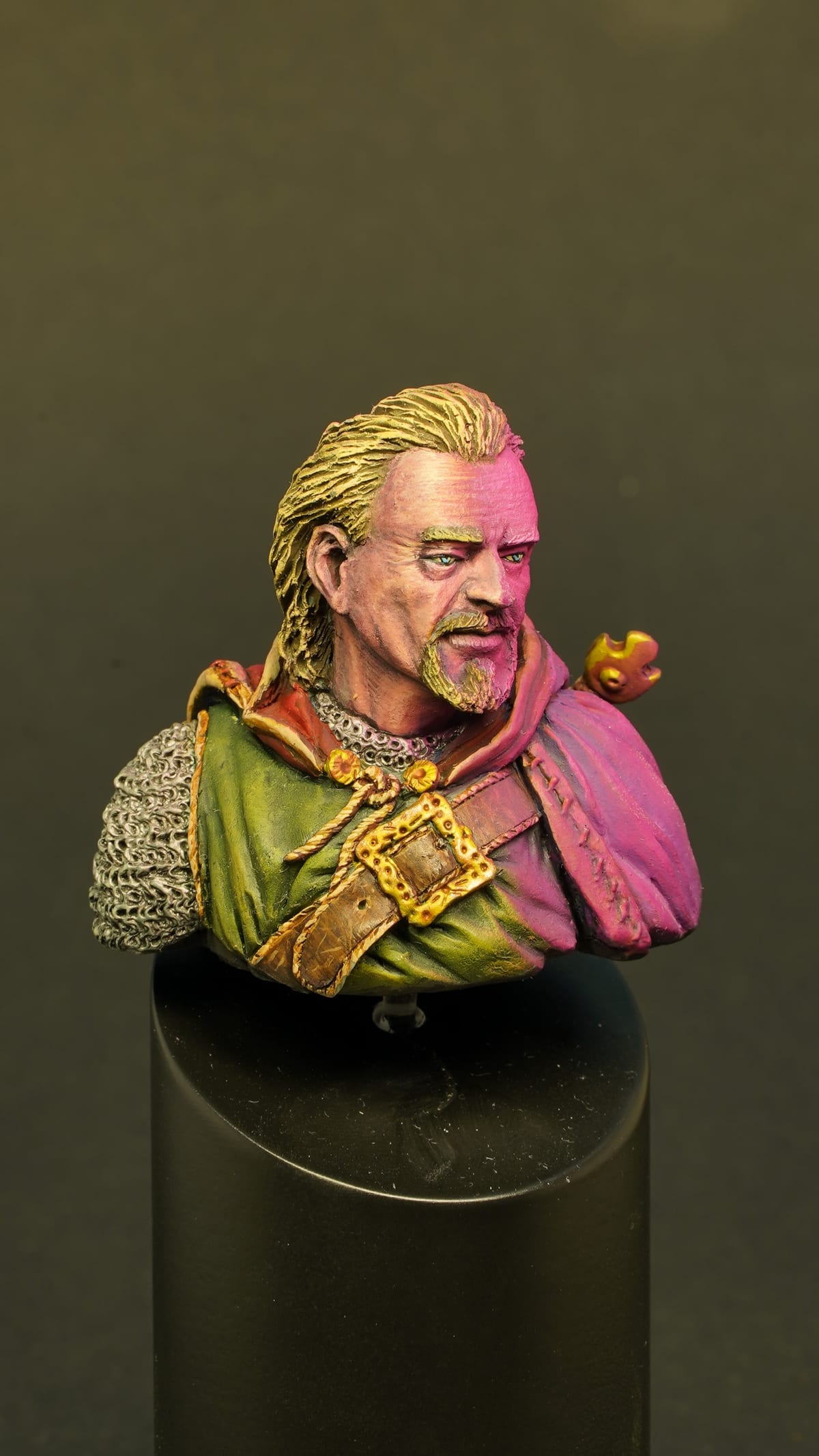 Bust of a blond man in a green and magenta cloak
