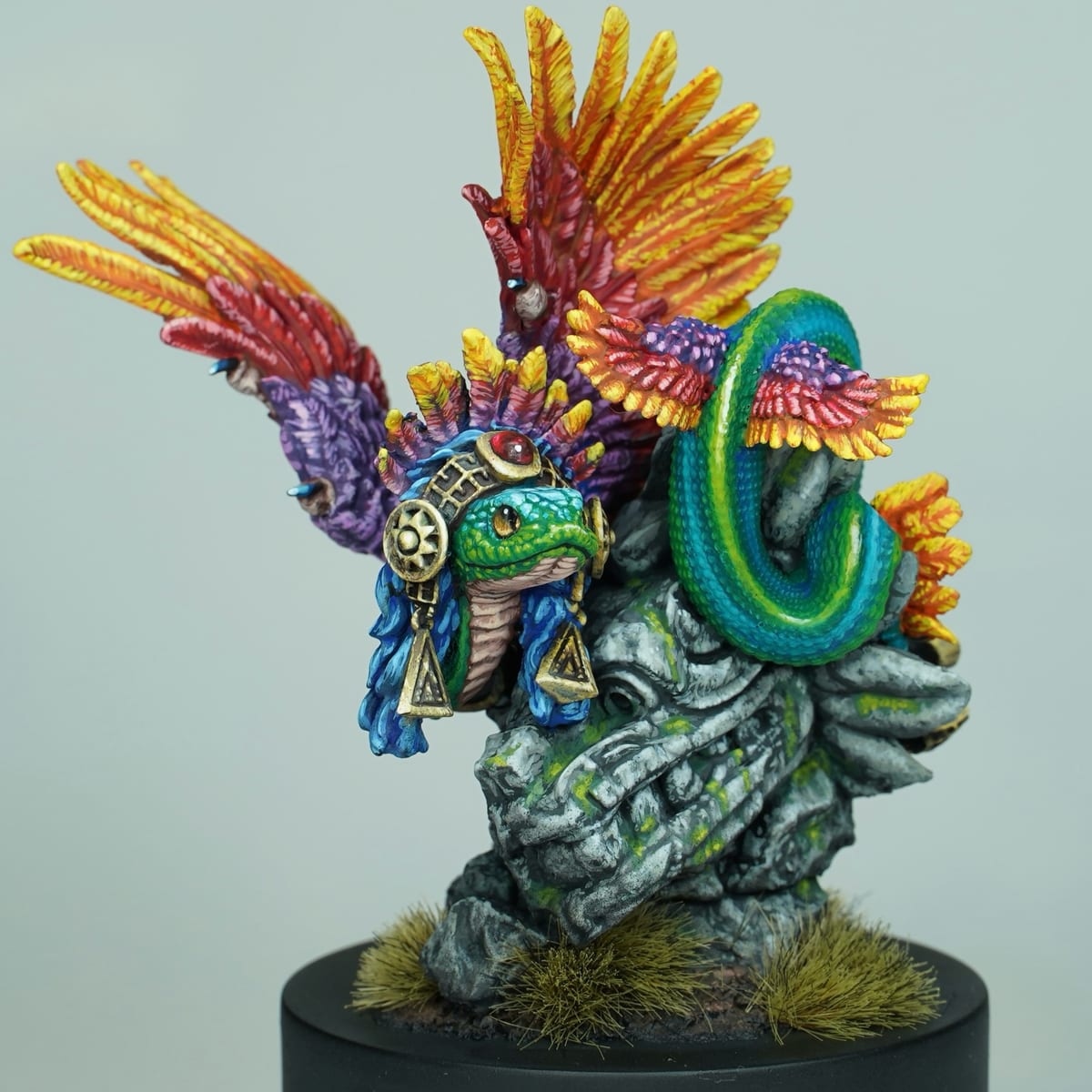 Quetzalcóatl : un serpent à plumes au plumage jaune, orange et violet, enroulé sur un socle de pierre sculptée