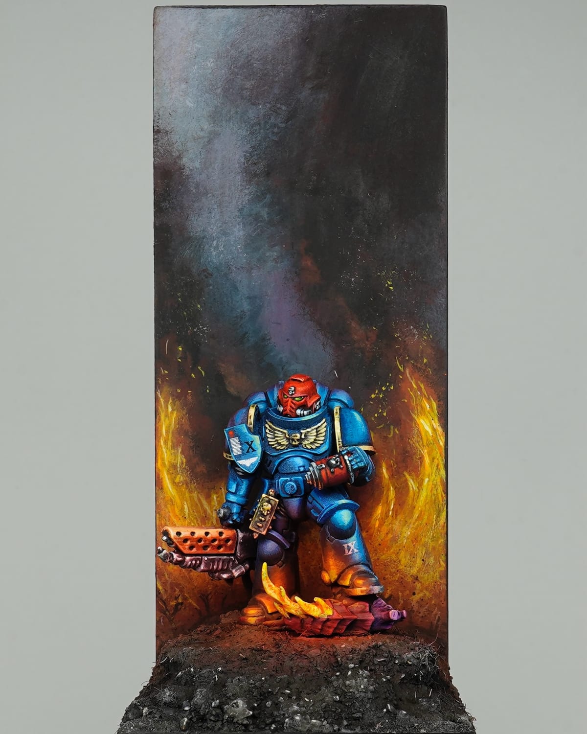 Sergeant Infernus en armure bleue avançant à travers des flammes peintes sur un haut décor