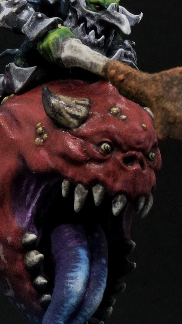 Close-up of the squig’s red face, teeth and tongue