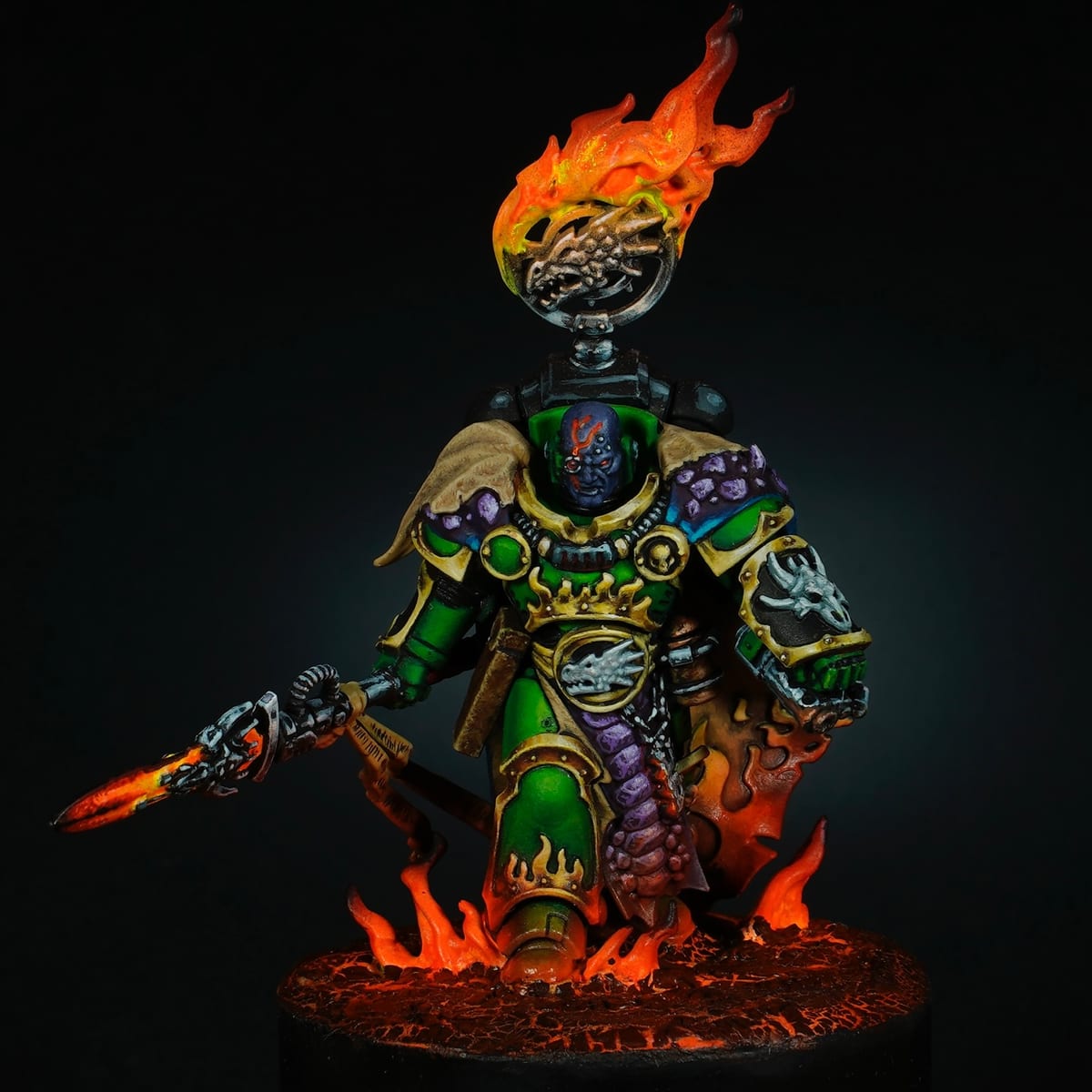 Vulkan He’stan con armadura verde y dorada, con llamas saliendo del casco y la lanza, sobre una peana en llamas